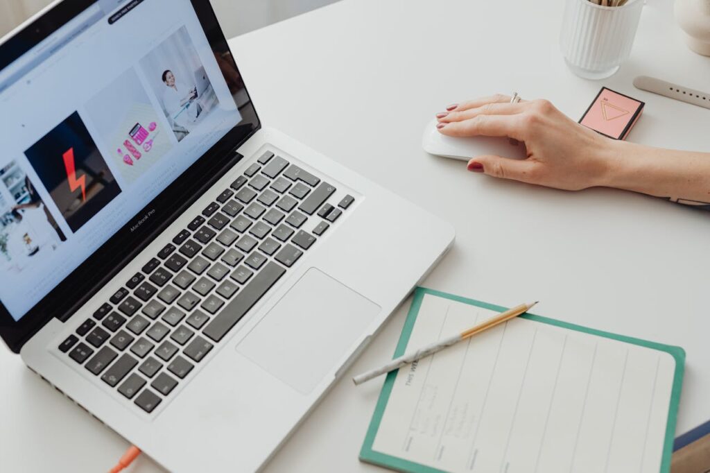 Close-up of a workspace featuring a laptop, mouse, and notepad for productive work.